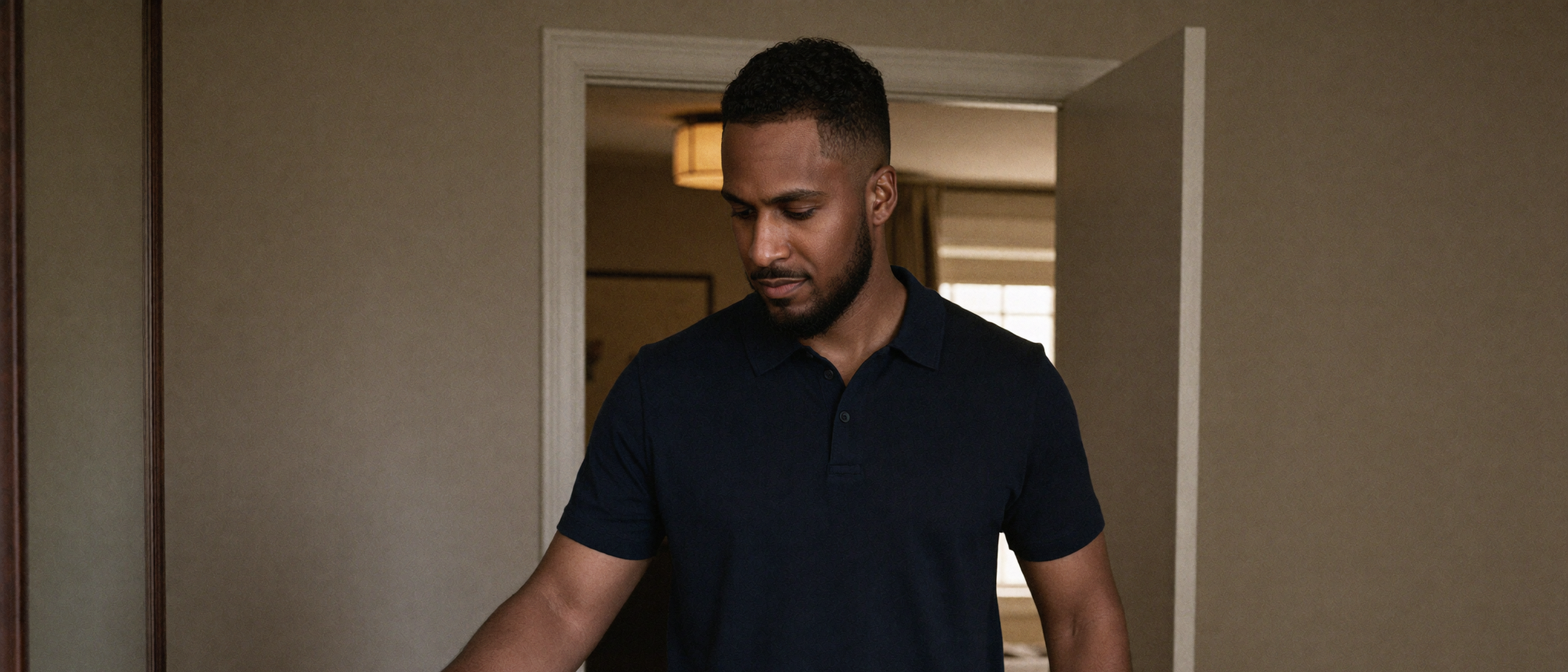 King The Kemist places his keys into a tray during a quiet morning ritual, dressed in a dark polo and tailored trousers